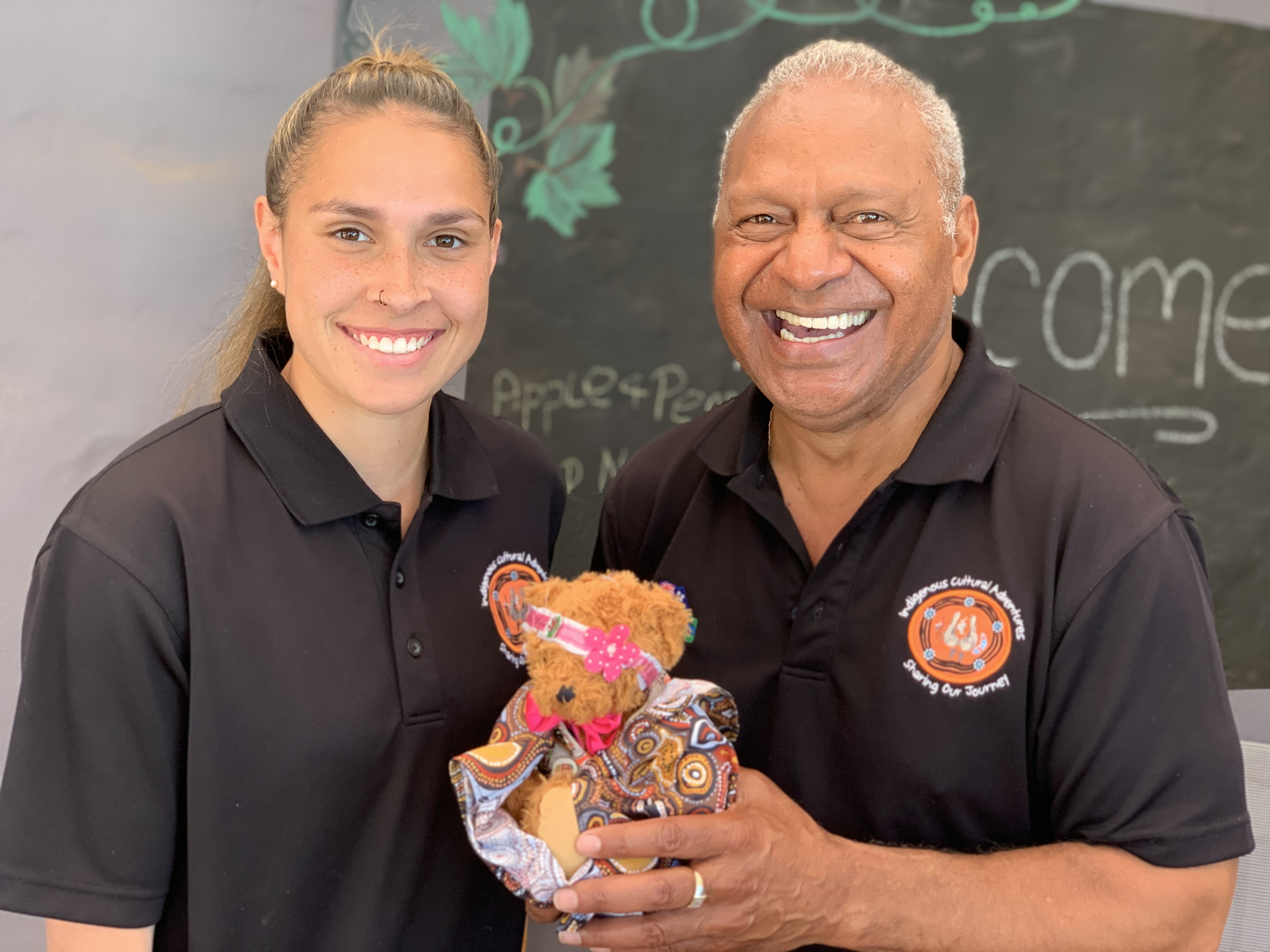 2 First Nation guides holding a teddy bear